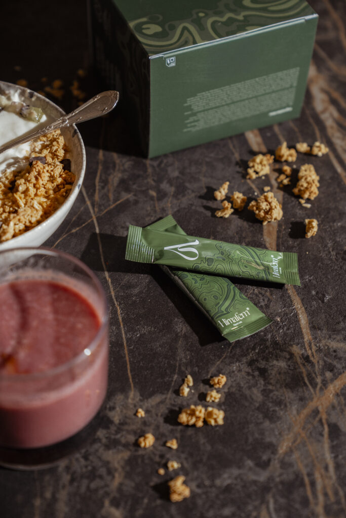 Stick de Himafem junto a frutas y cereales, símbolo de energía natural y bienestar femenino.