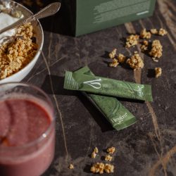 Stick de Himafem junto a frutas y cereales, símbolo de energía natural y bienestar femenino.